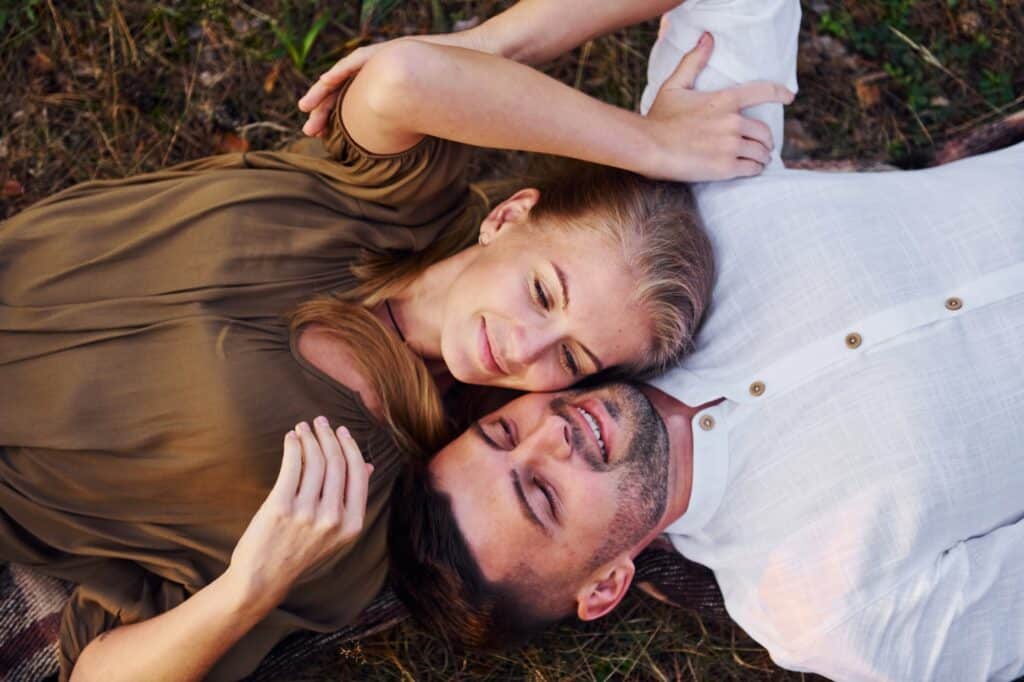 Happy couple is outdoors laying down on the ground